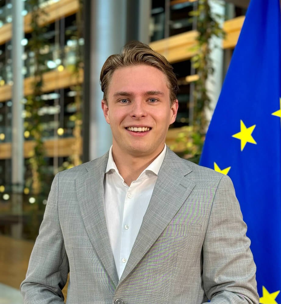 Daniel V. Müller, Gründer von DVMethods, im grauen Anzug vor der Europaflagge